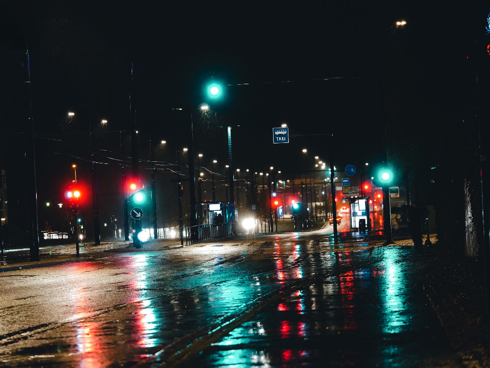 Teal traffic signals and orange reflections on a wet night street